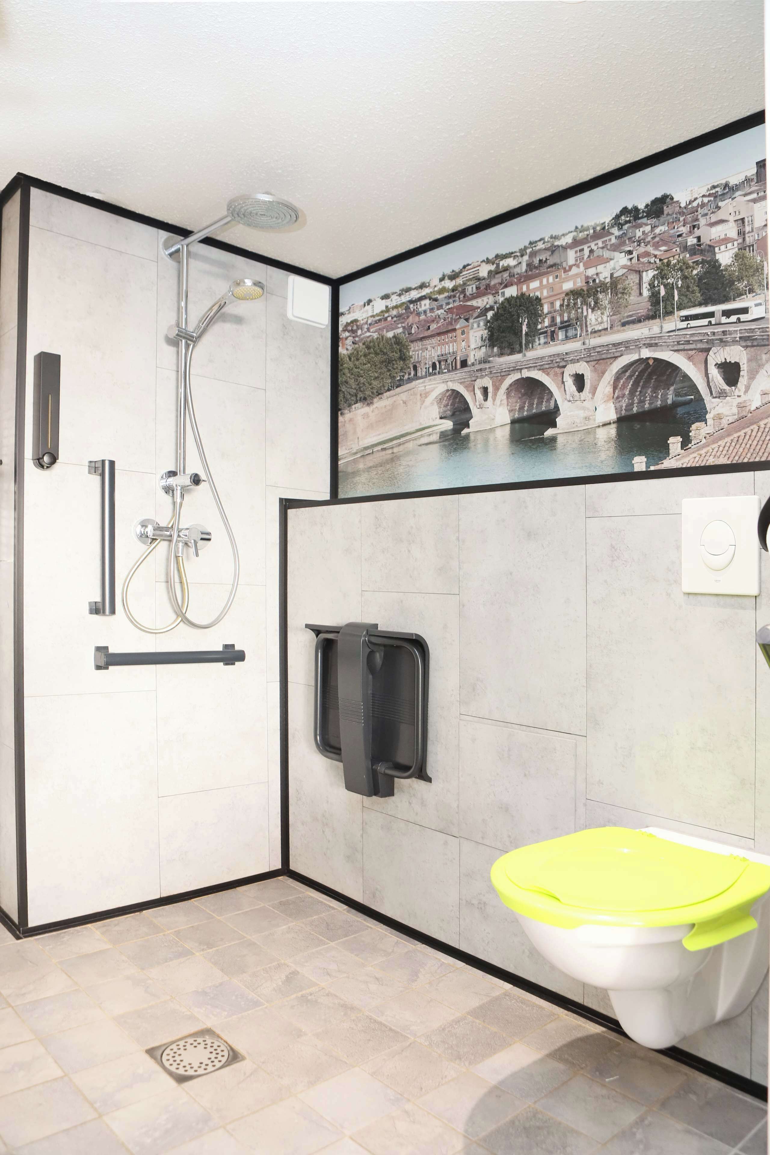 Un baño moderno con ducha, inodoro y secador de manos integrado en la pared.