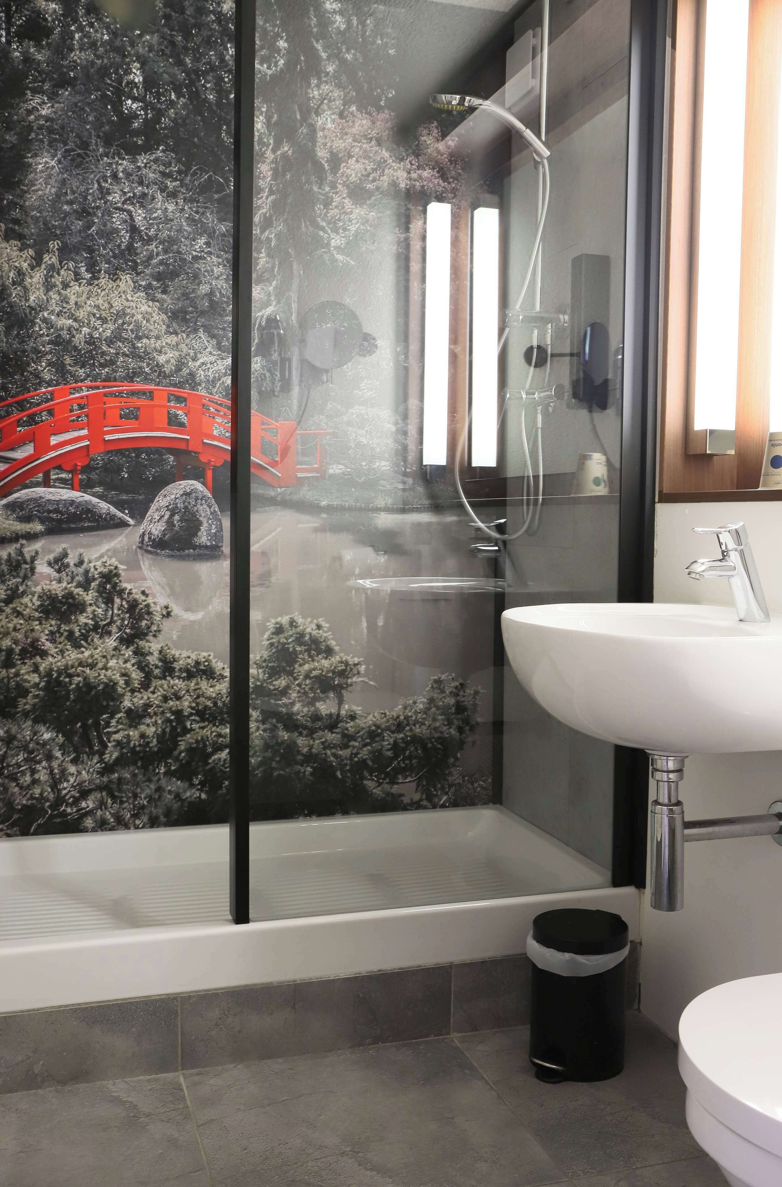 A modern bathroom with a glass shower enclosure, a white sink, and a bathtub.