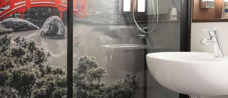 Une salle de bain moderne avec une douche à l’italienne en verre, un lavabo blanc et une baignoire.
