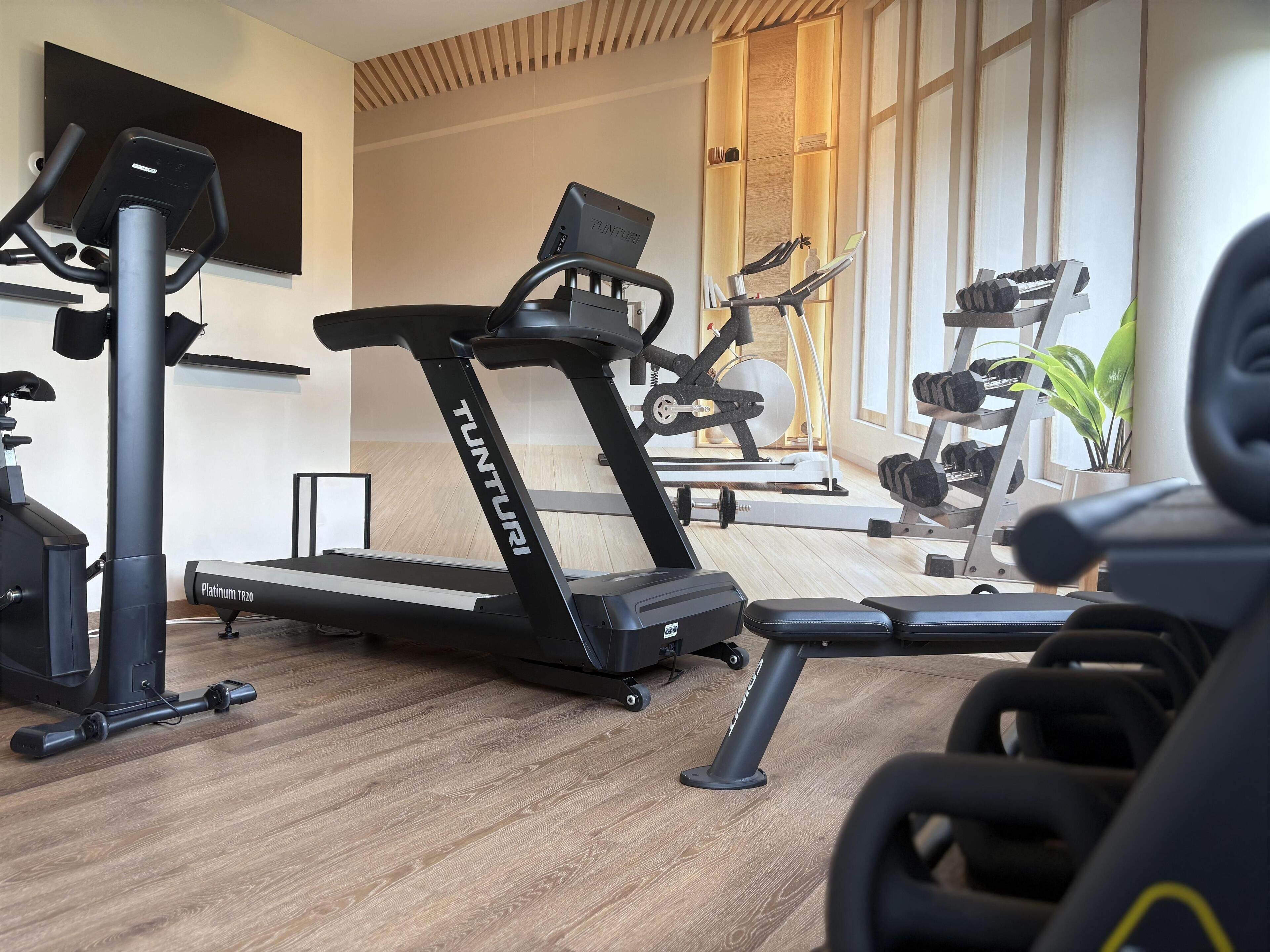 A home gym with a Tunturi treadmill, weight bench, and various exercise equipment.
