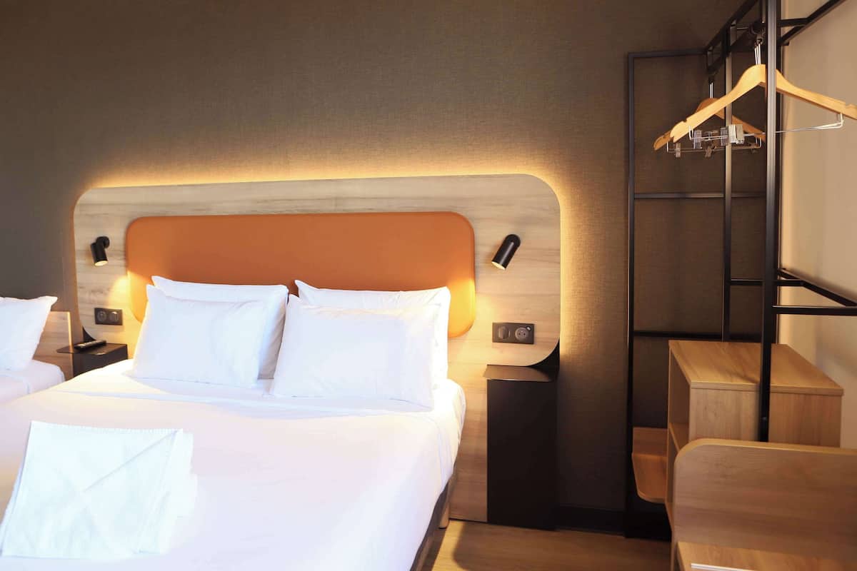 A neatly made bed with white linens, a wooden headboard, and a bedside table with a lamp.