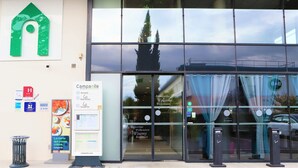 A hotel entrance with a large glass facade, a welcome sign, and a digital clock. - Campanile PRIME - Toulouse Sud Balma Cité de l'Espace (Toulouse)