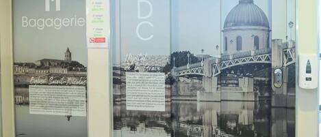 Un ascensor con superficie reflectante que muestra un edificio histórico y un puente.