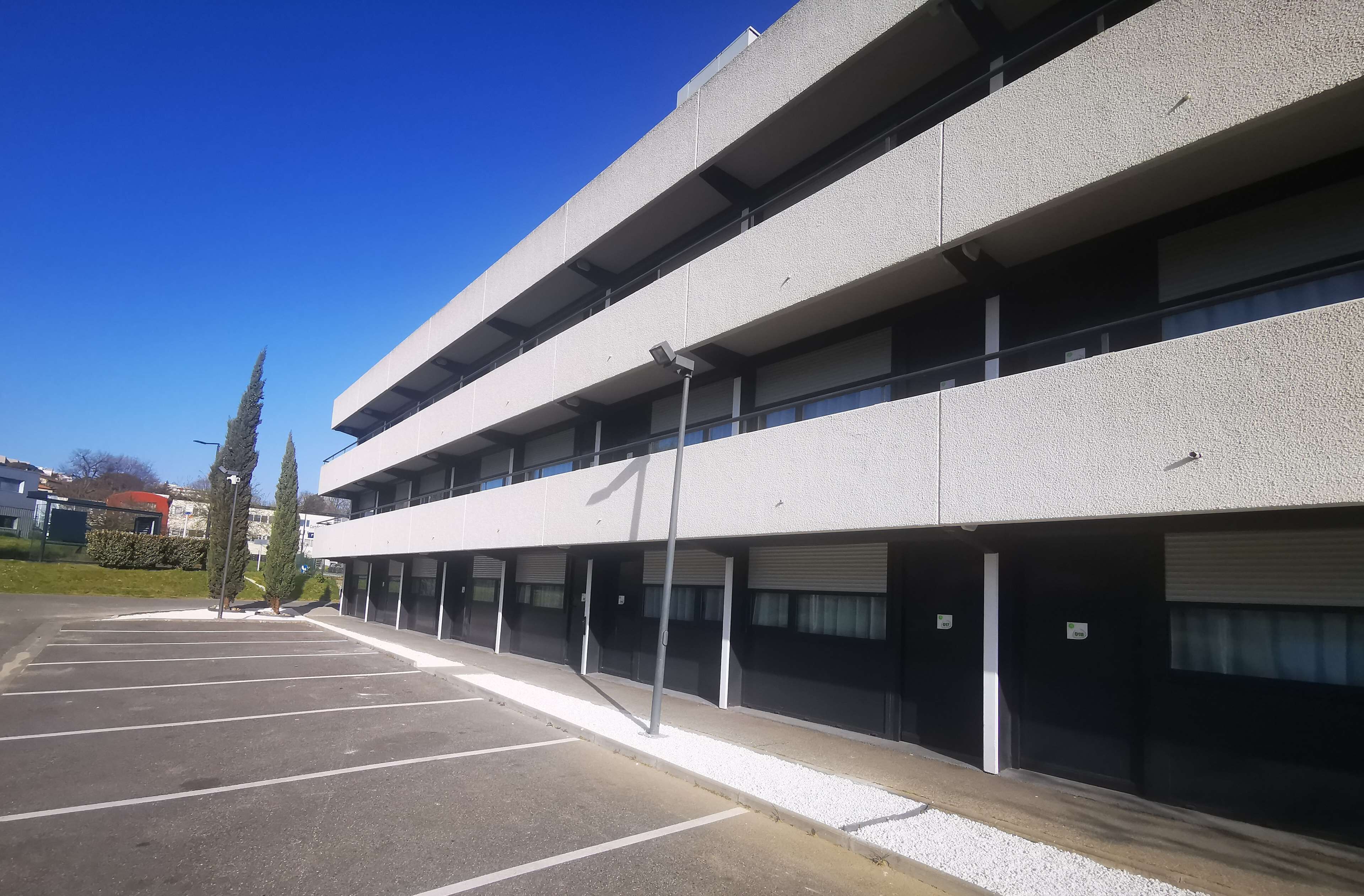 Een meerlaagse parkeergarage met modern design, met een reeks parkeerplaatsen en een overdekte doorgang.