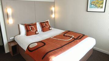 A neatly made bed with a brown blanket and two pillows, a headboard with wall-mounted lights, and a framed map on the wall.