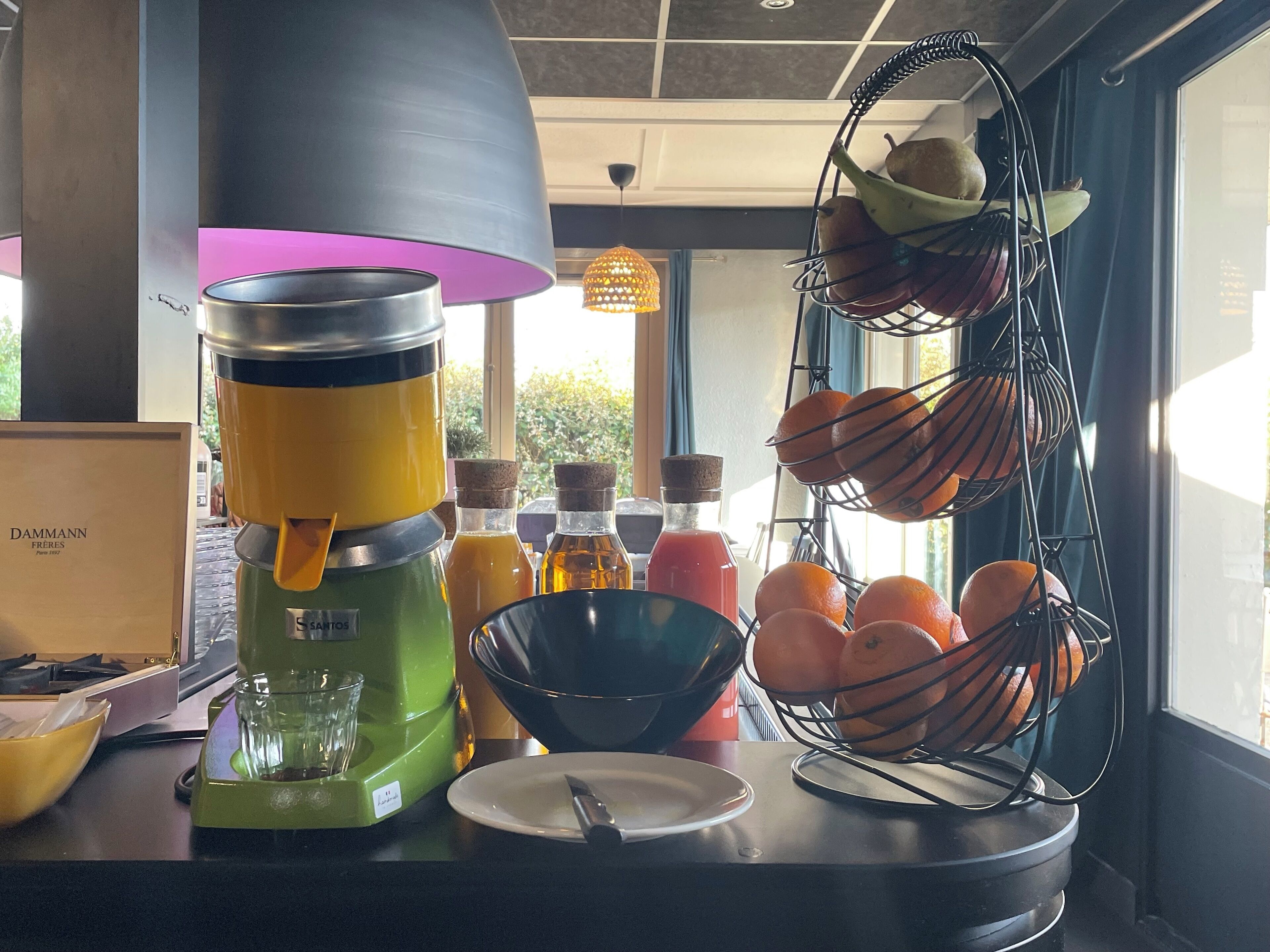 Een keukentoog met een koffiezetapparaat, een blender, een fruitmand en een fles sap.