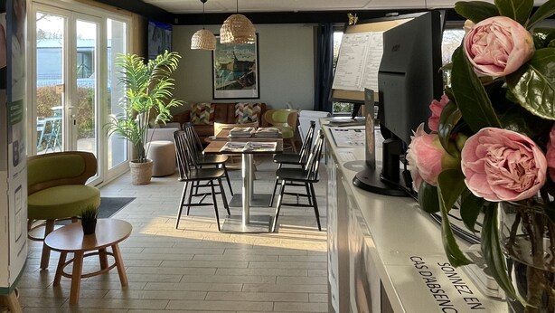 Un interior moderno con mostrador de recepción, zona de estar y ventanas amplias.