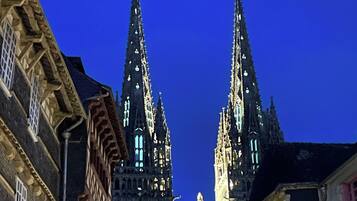 A historic building with two prominent spires and a central tower, surrounded by traditional European architecture.