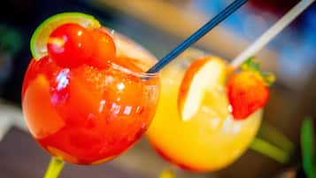 Two fruit-shaped cocktails with straws, garnished with slices of lime and orange.