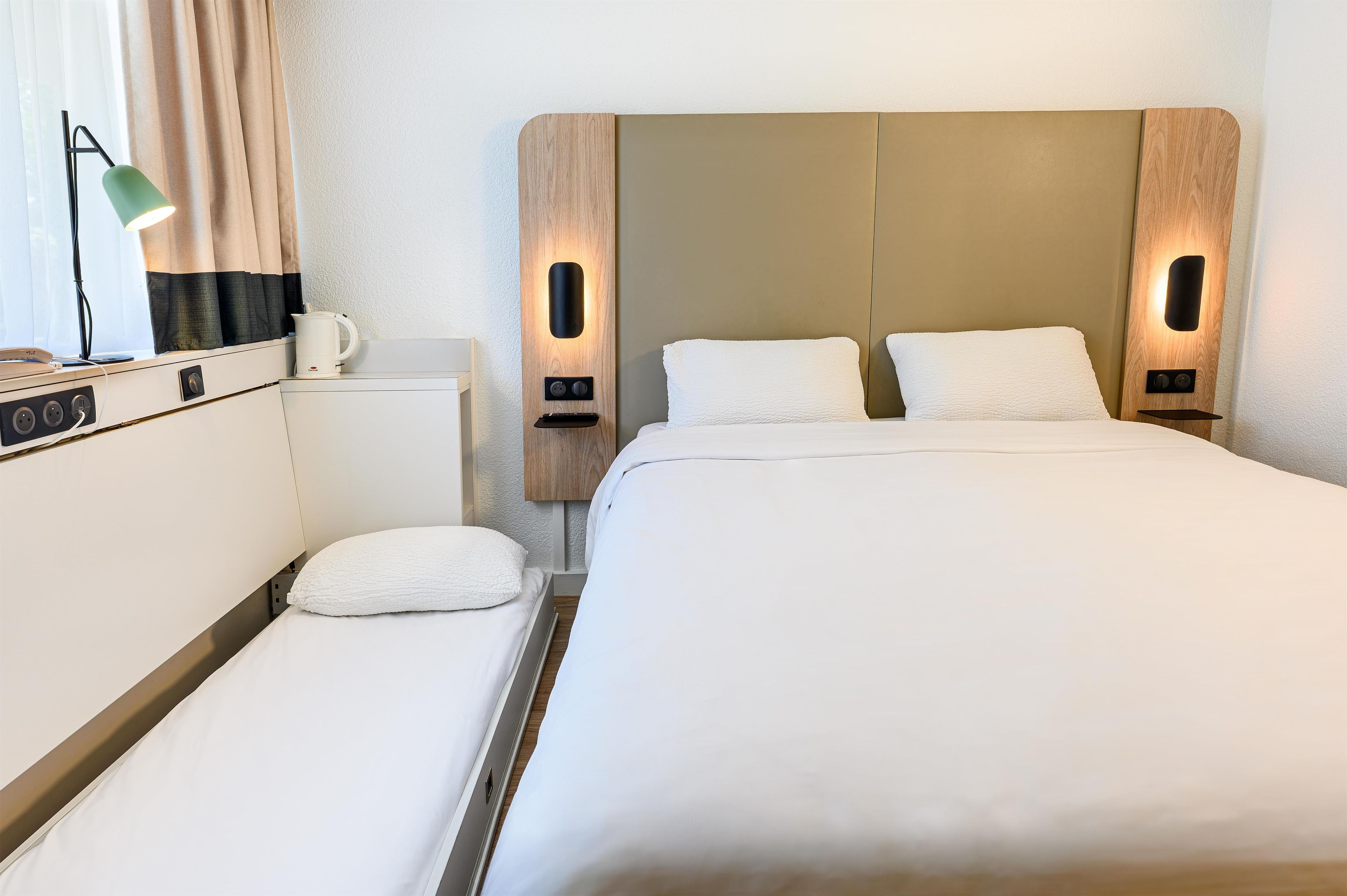 A hotel room with a bed, bedside tables, a lamp, and a coffee maker.