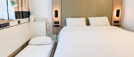 A hotel room with a bed, bedside tables, a lamp, and a coffee maker.