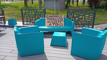 Sitzbereich im Freien mit einem Schild, auf dem 'CAMPANILE TERRASSE OUVERTE A TOUS' steht.