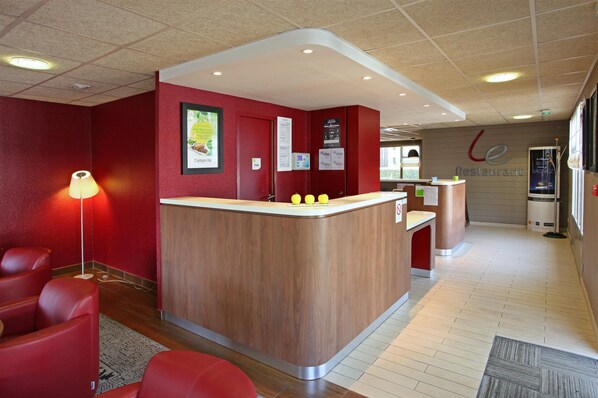 A restaurant interior with a wooden counter, red walls, and a reception desk.