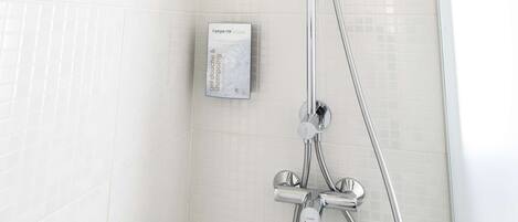 Una ducha con cabezal de ducha manual y panel de control en la pared.