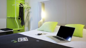 Une chambre d’hôtel équipée d’un lit, d’un ordinateur portable, d’un téléphone portable et d’un porte-vêtements.