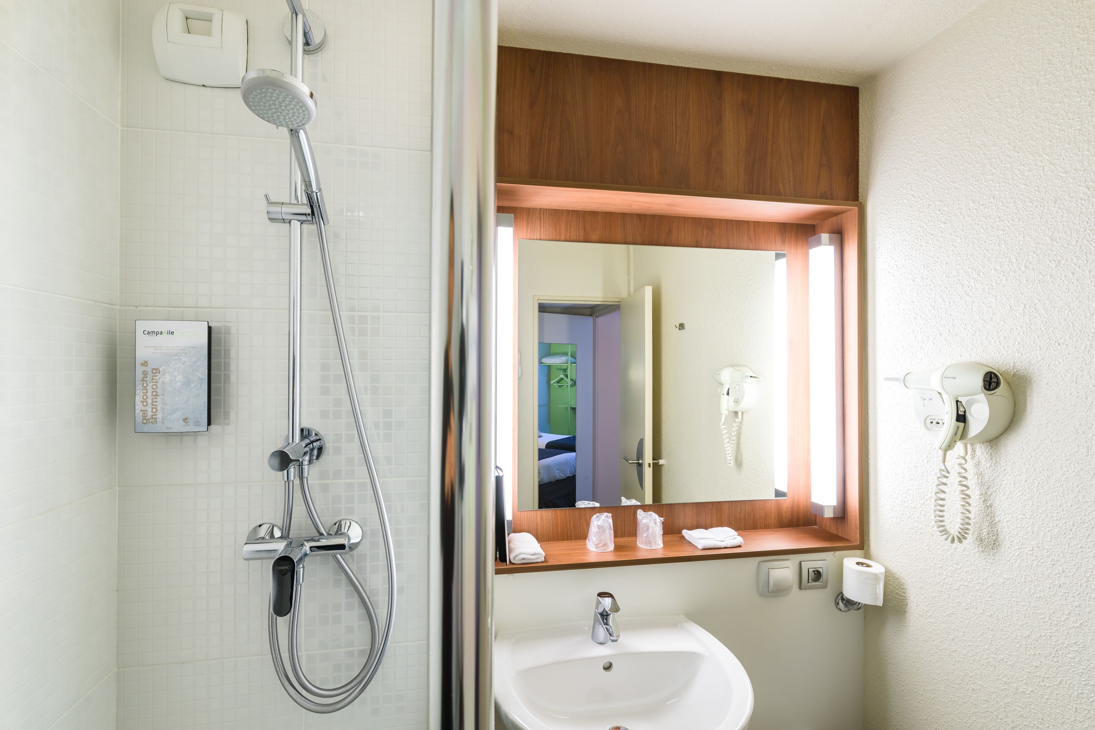 Een moderne badkamer met een douche, wastafel en spiegel.