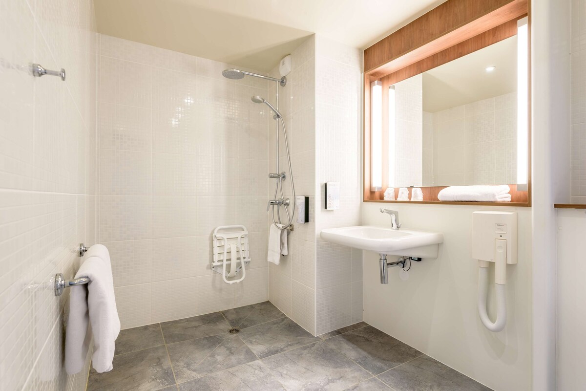 Ein modernes Badezimmer mit Dusche, Waschbecken und Spiegel.