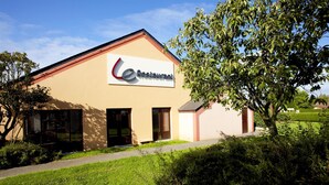 A building with a sign reading "Restaurant" and a tree in front.