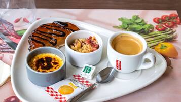 Bandeja de desayuno con un croquembouche, dos recipientes pequeños de comida, una taza de café y una cuchara.