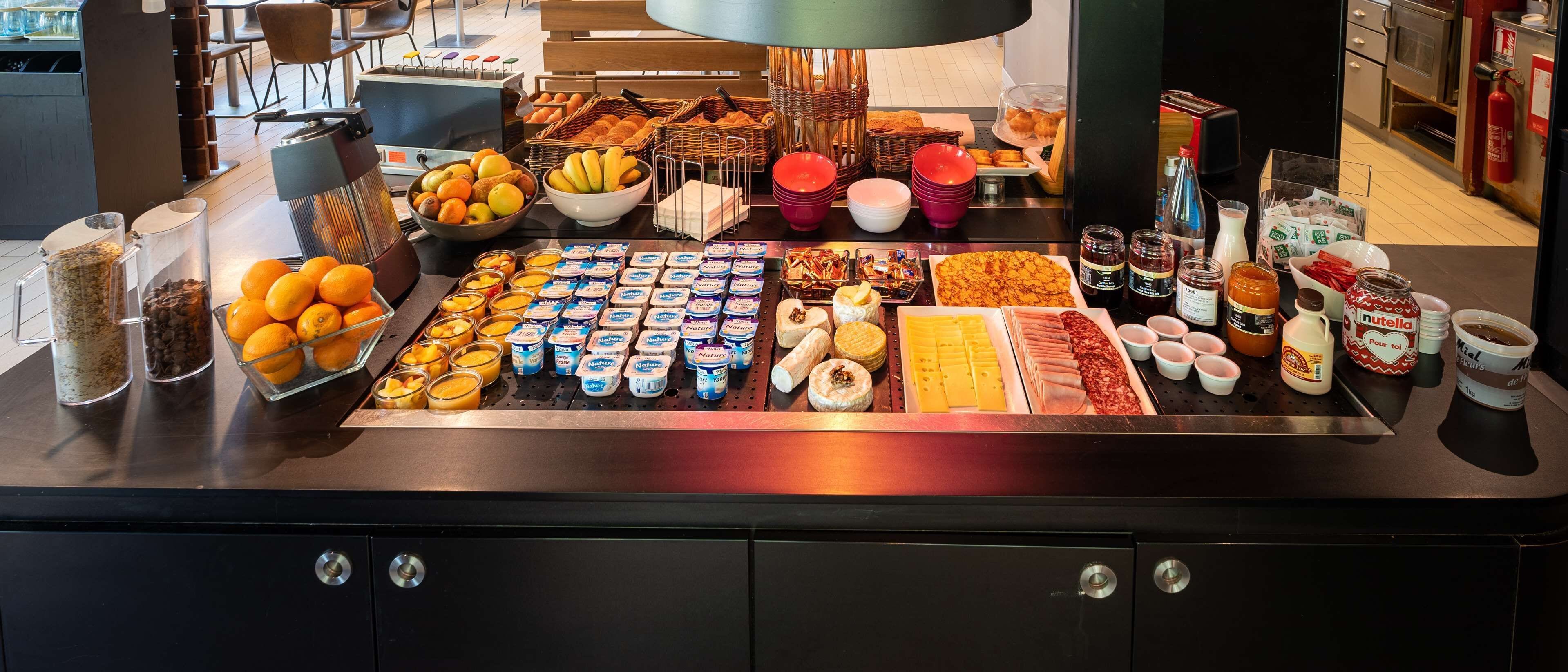 A buffet with various food items including fruits, cheeses, and condiments.