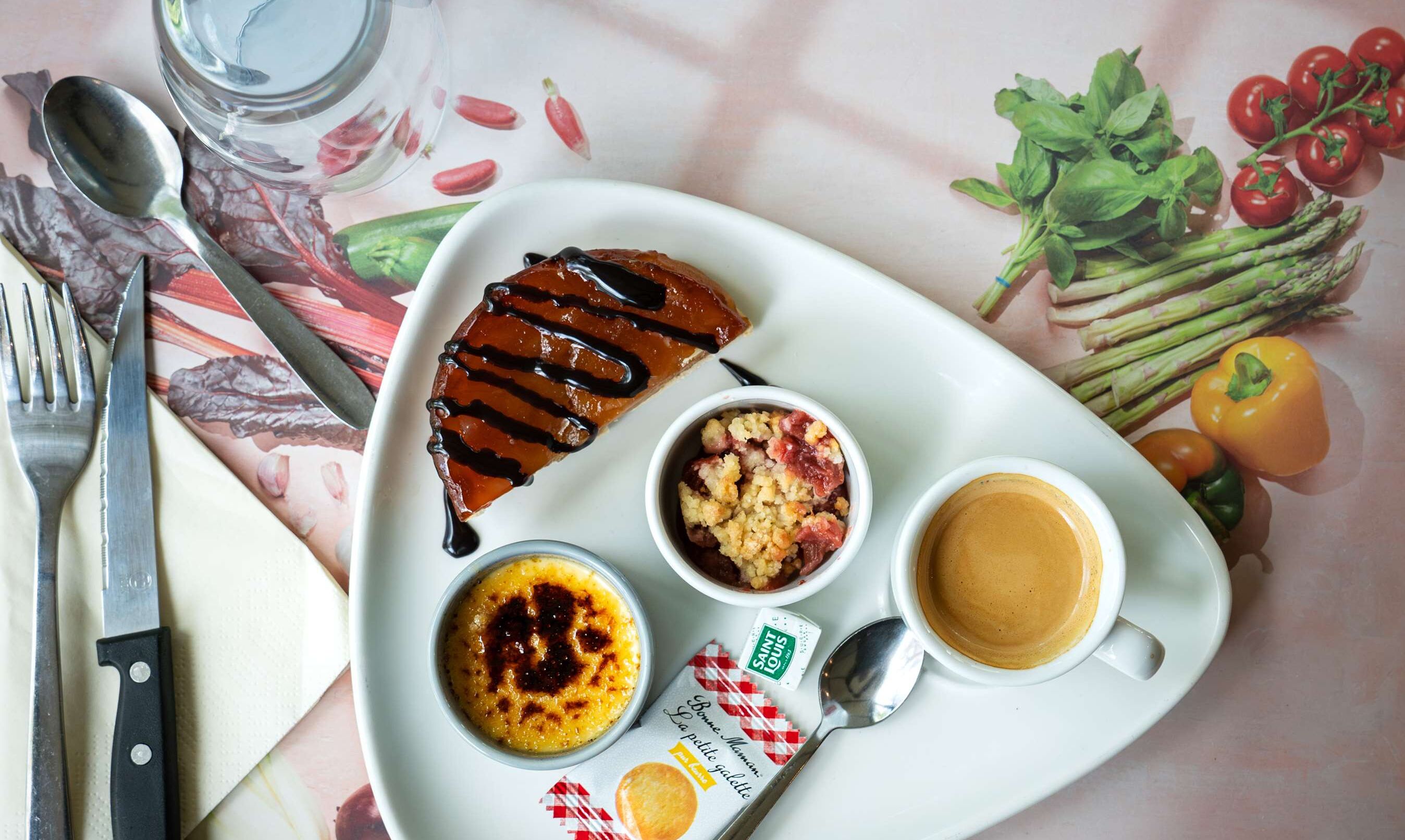 Un plato con postre, un bol de comida desmenuzada y una taza de café, junto con algunas verduras y una cuchara.