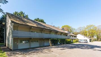 Un motel doté d’un parking couvert, d’une construction à un seul étage et d’un petit bâtiment attenant.