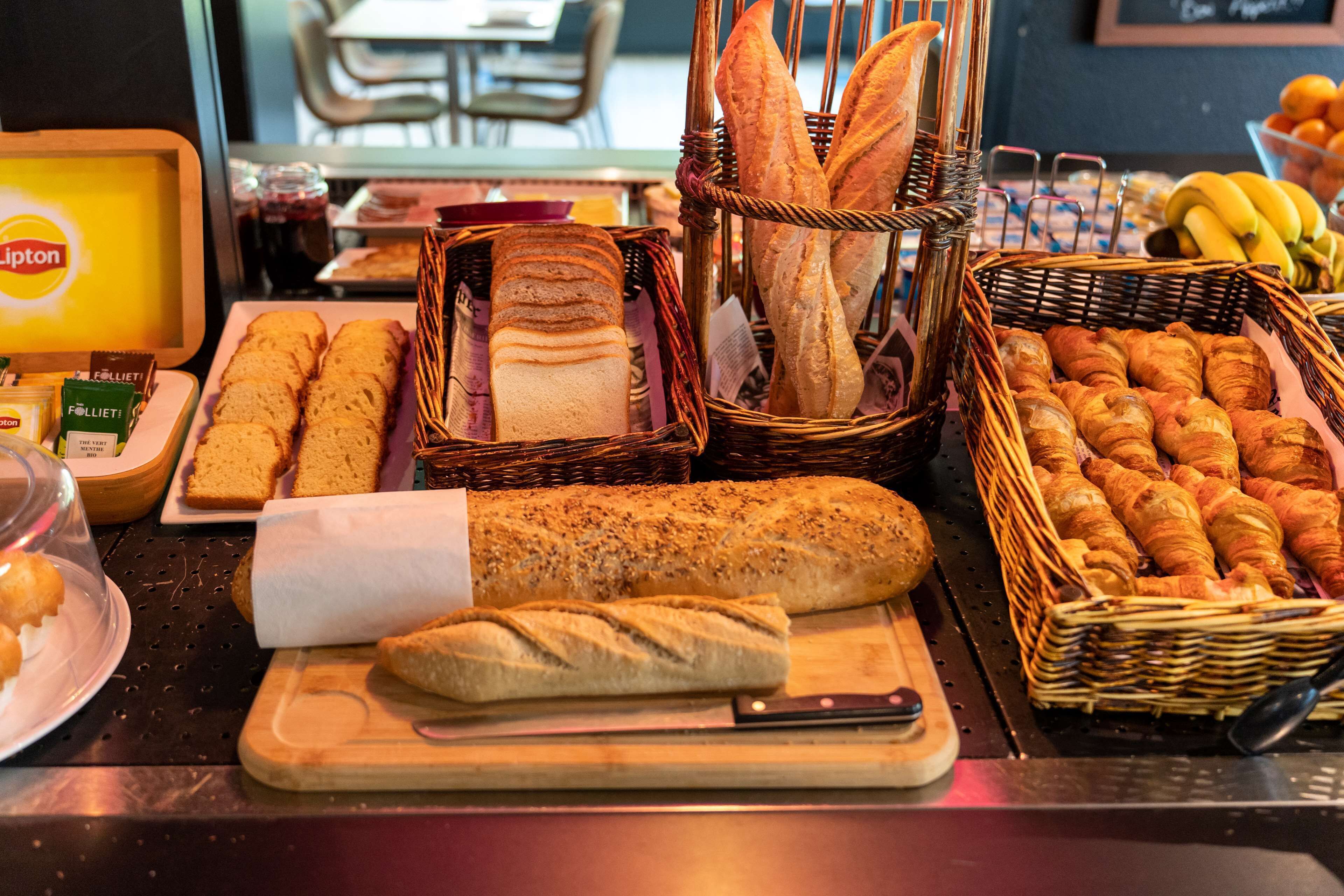 A variety of breads and pastries on display, including baguettes, croissants, and a loaf of bread on a cutting board.
