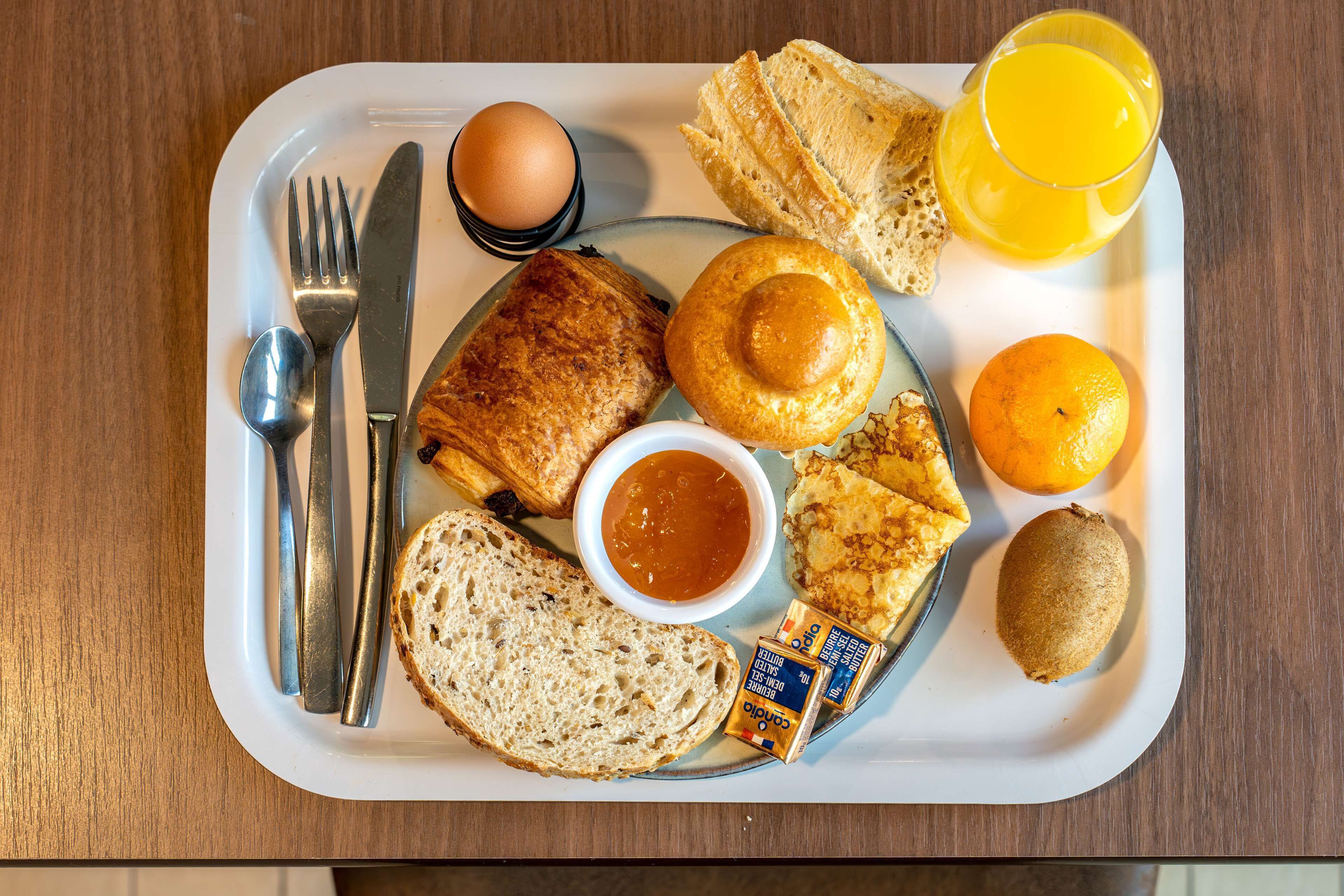 A breakfast tray with toast, eggs, orange juice, and butter.