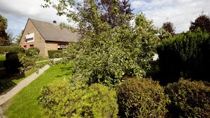 A building with a brick facade and a sloped roof, surrounded by well-maintained greenery and a clear sky. - Campanile NATURE - Rouen Nord Mont Saint Aignan (Mont-Saint-Aignan)