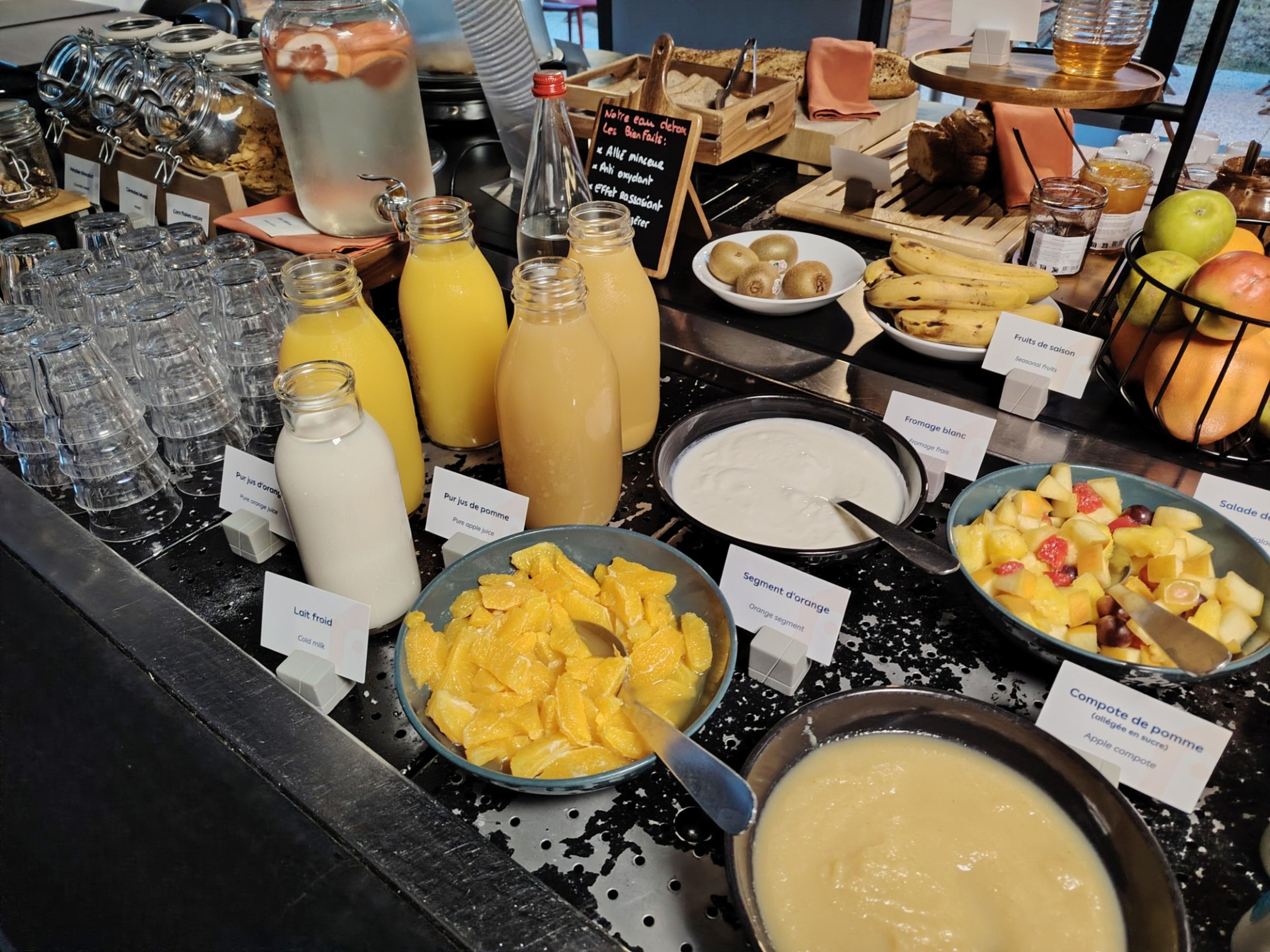 Un buffet proposant une variété d’aliments et de boissons, notamment des fruits, des jus et des produits laitiers.