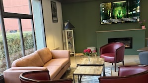 Een moderne woonkamer met een bank, twee fauteuils, een salontafel en een open haard.