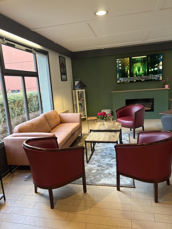 Un salon moderne comprenant un canapé, deux fauteuils, une table basse et une cheminée.