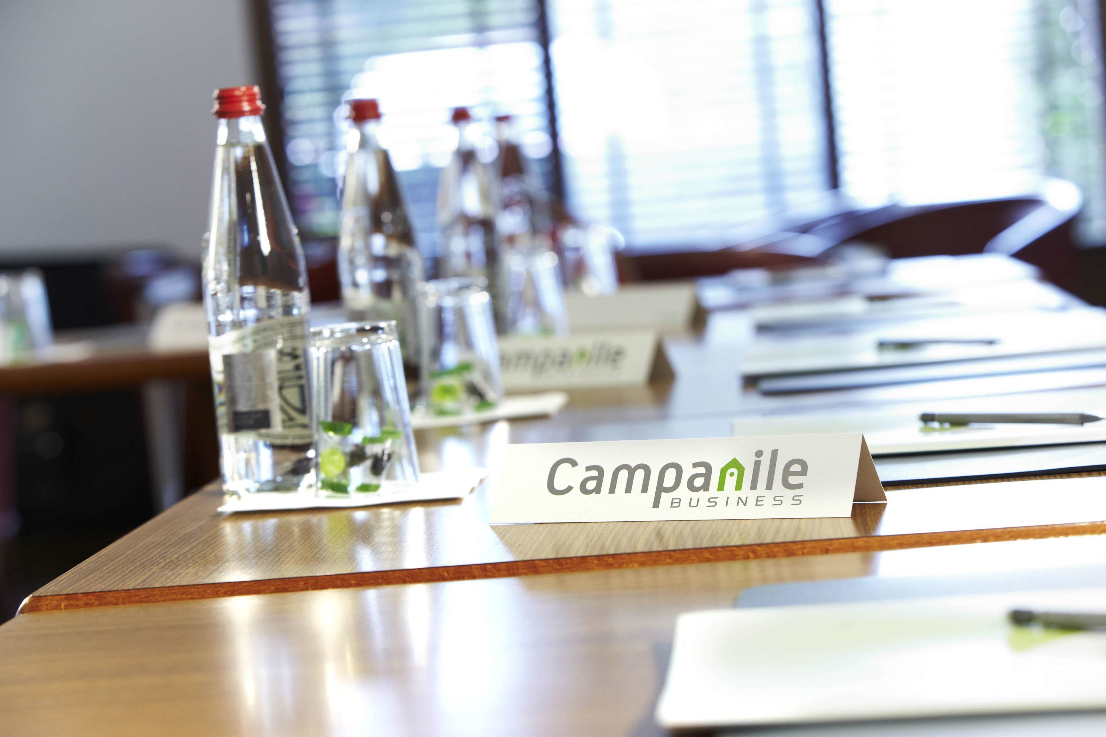 A conference table with nameplates, water bottles, and a sign reading "Campanile Business".