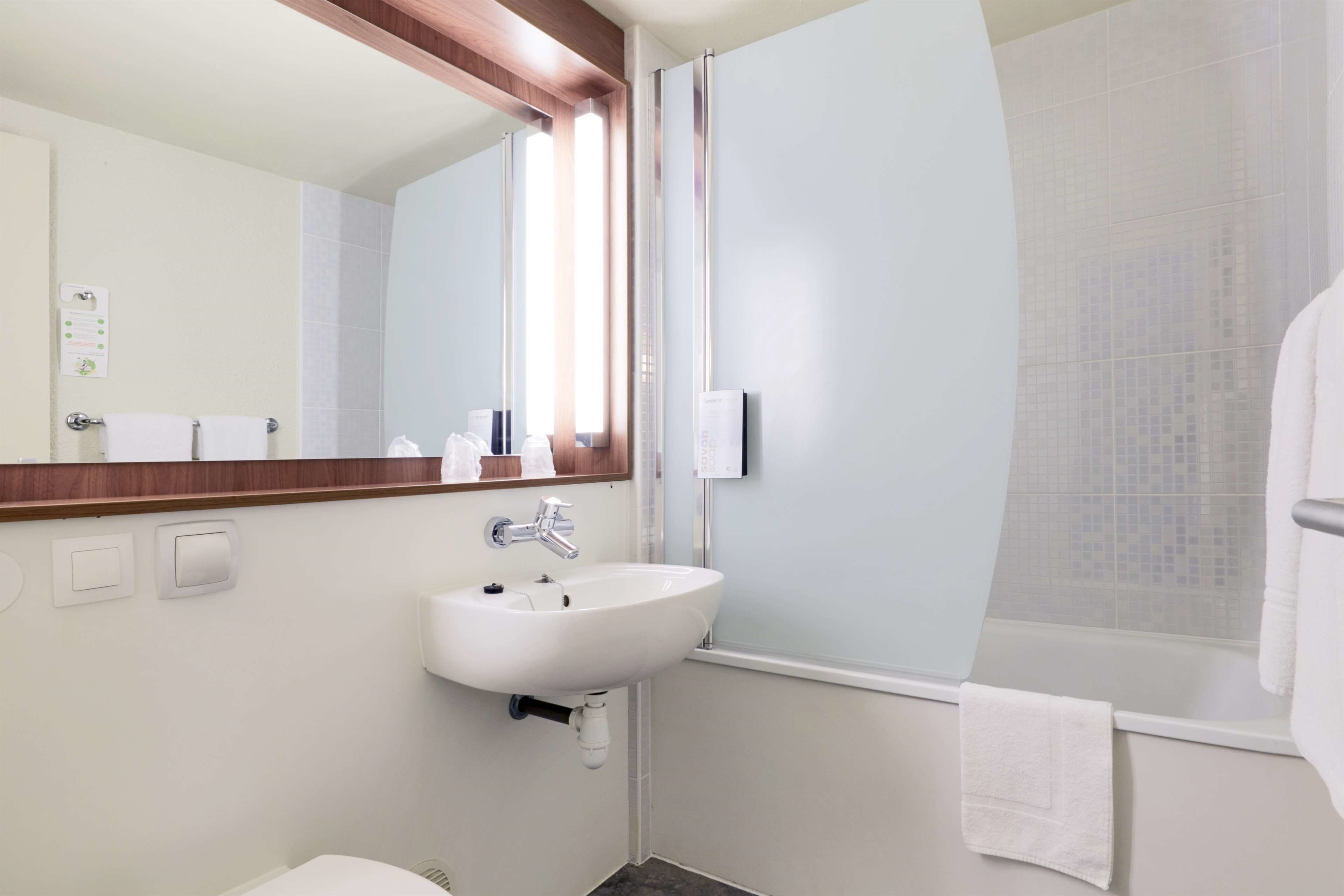 Een moderne badkamer met een witte wasbak, een spiegel en een douche.