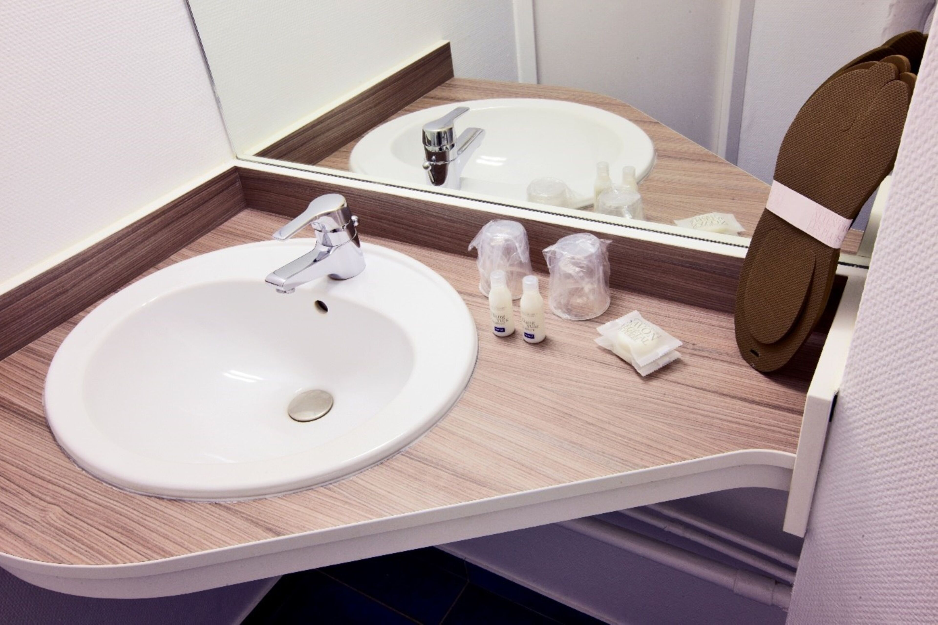 A bathroom with a white sink, a mirror, and toiletries on the counter.