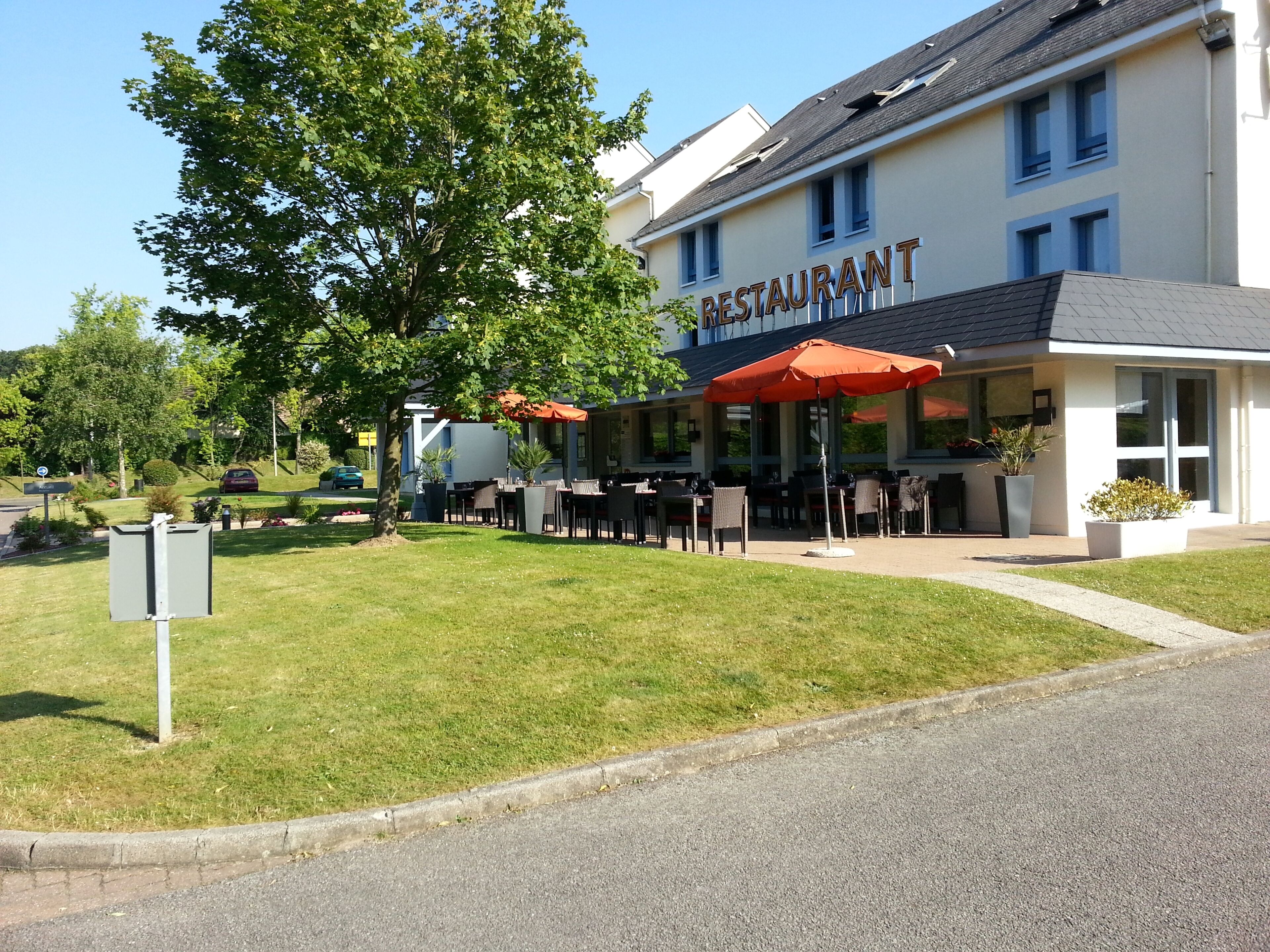 Ein Restaurant mit Außenbereich, einer überdachten Terrasse und einem Gebäude mit der Aufschrift 'RESTAURANT'.