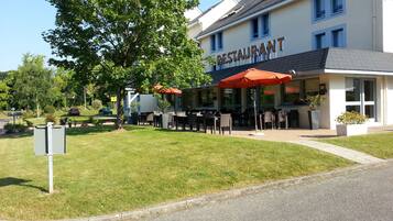 Ein Restaurant mit Außenbereich, einer überdachten Terrasse und einem Gebäude mit der Aufschrift 'RESTAURANT'.