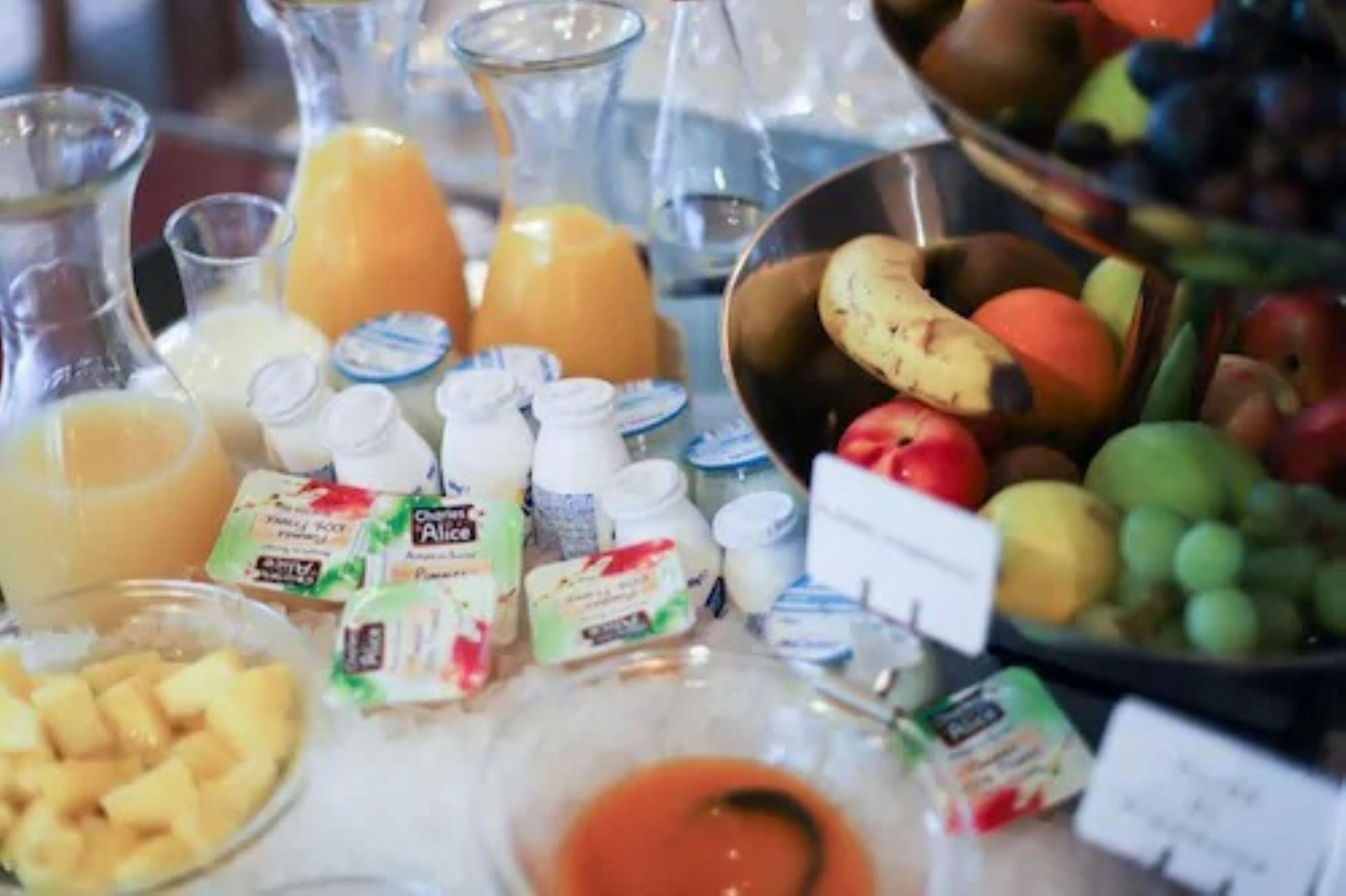 A table with various food items and beverages, including fruits, juices, and dairy products.