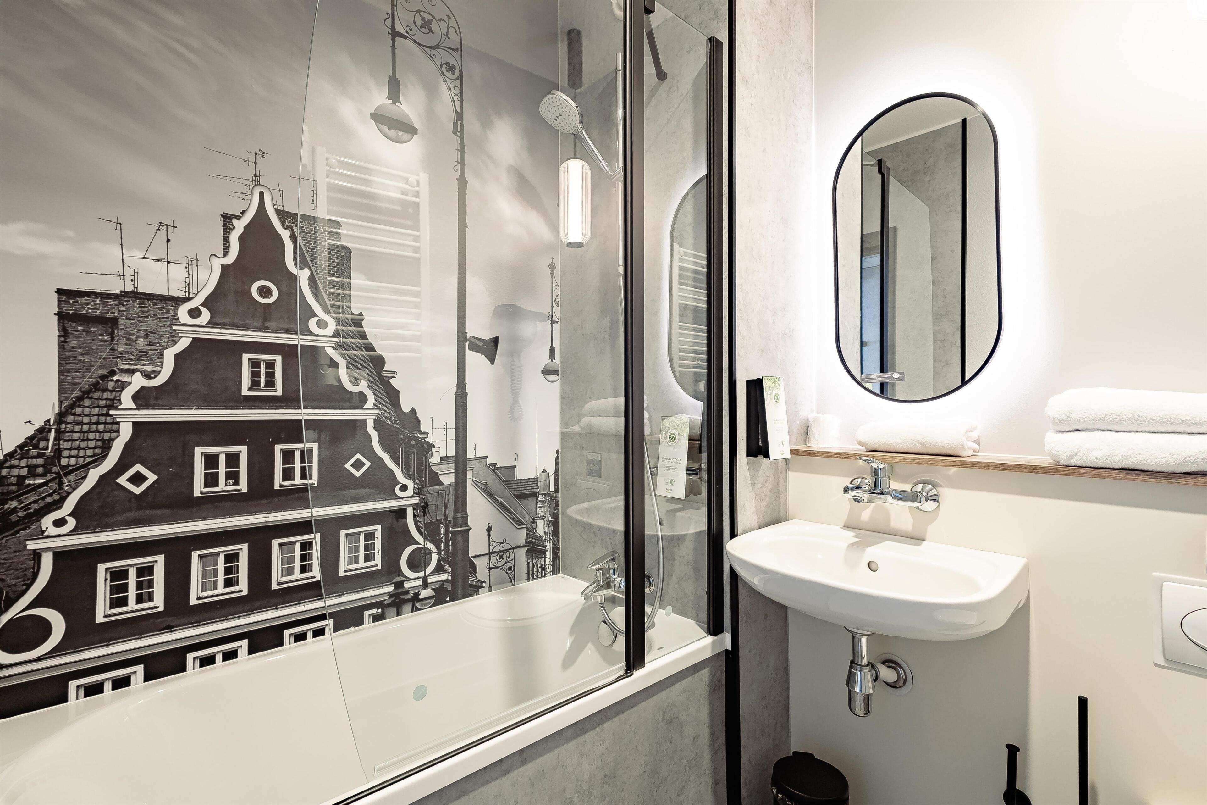 Et moderne badeværelse med et glasbadeværelse, en hvid vask og et spejl.