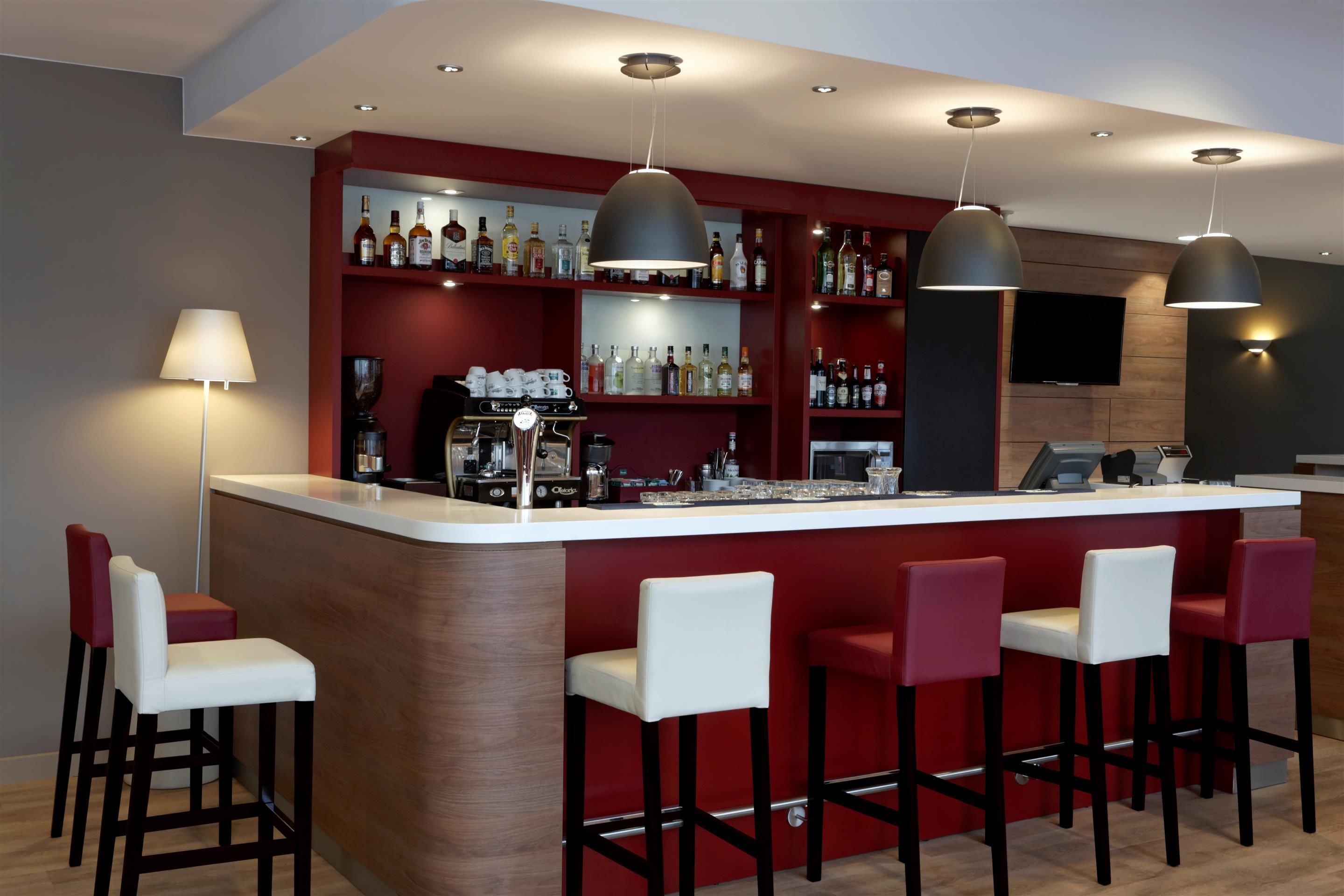 Zona de bar con una barra larga, varios taburetes y una variedad de botellas en estantes.