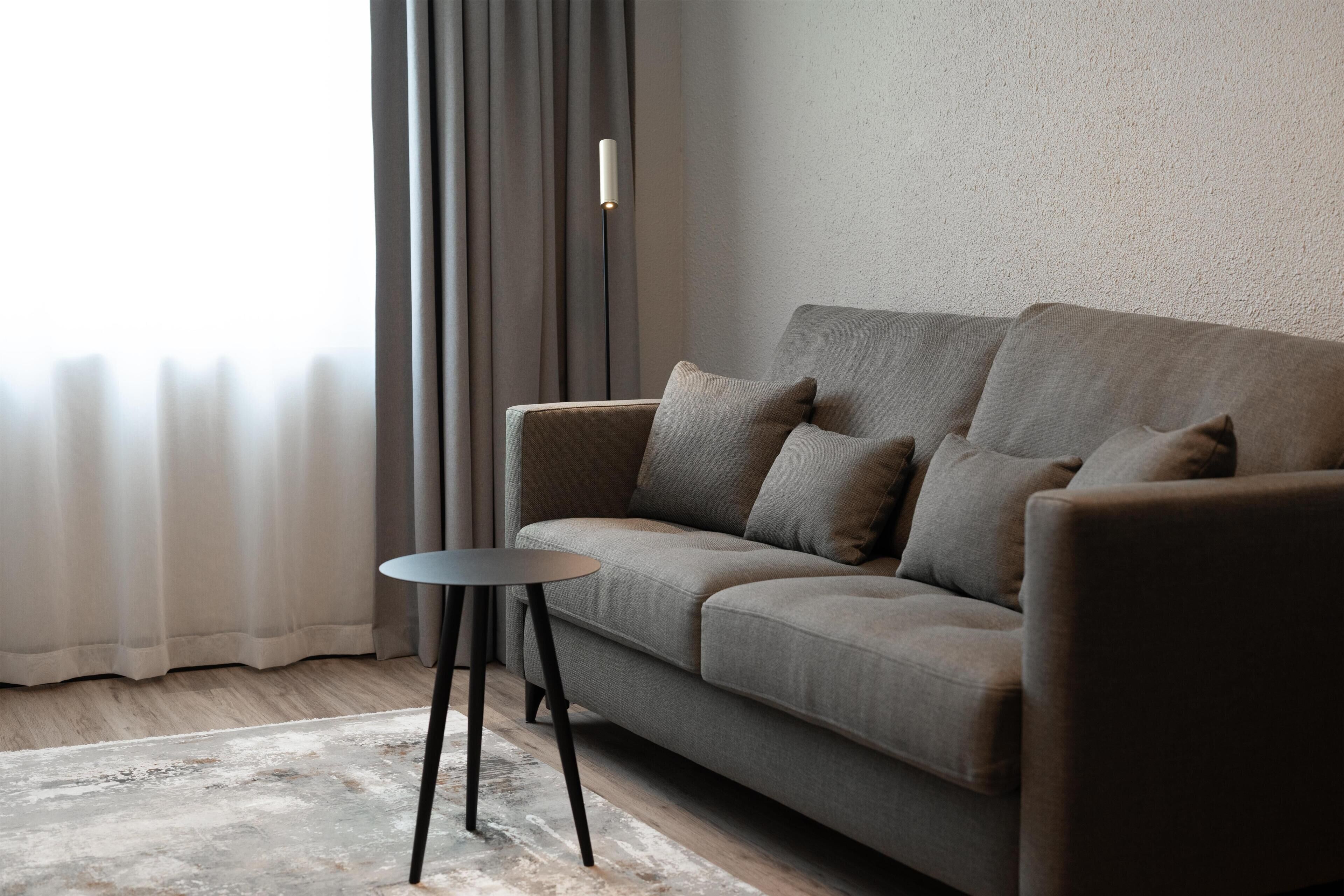 A modern living room with a sofa, a small round table, and a floor lamp.