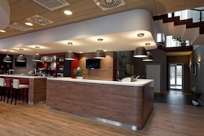 A modern hotel lobby with a central reception desk, bar area, and seating. - Campanile PRIME - Wroclaw Stare Miastro (Wroclaw)