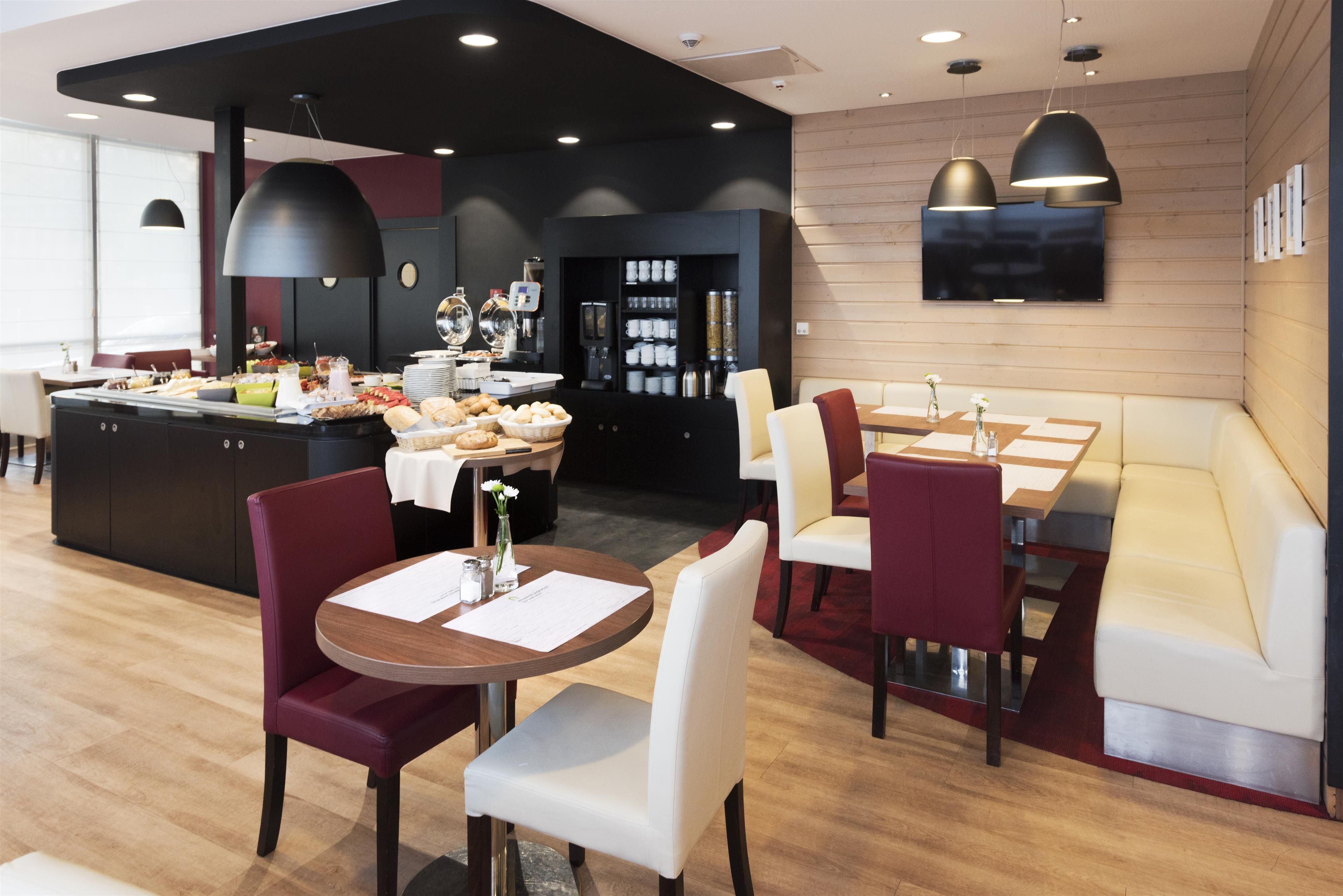 A modern dining area with a buffet, seating arrangements, and a television mounted on the wall.