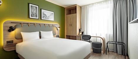Habitación de hotel con cama, escritorio, silla y vistas al exterior.