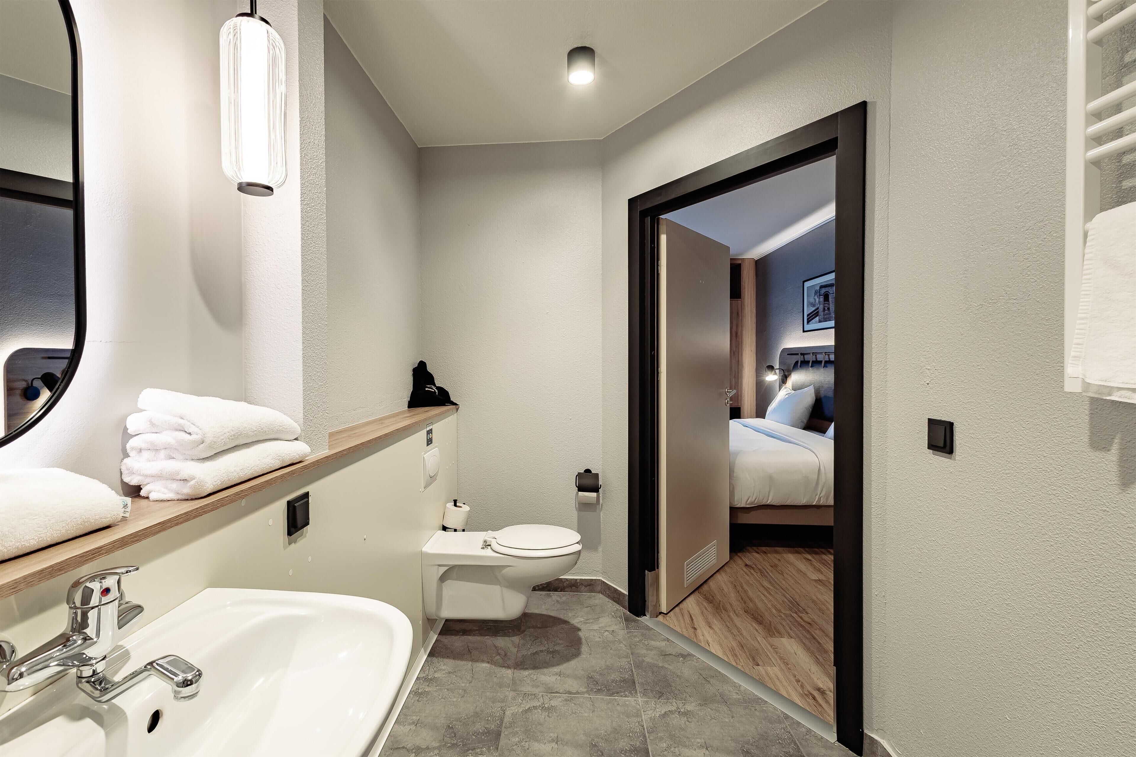 A modern bathroom with a sink, toilet, and mirror.