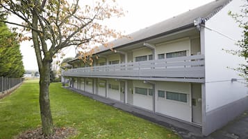 Een modern gebouw met een plat dak, meerdere garagepoorten en een verzorgd gazon.