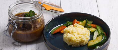A meal with a glass jar of sauce and a plate of vegetables and mashed potatoes.