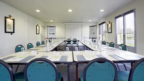 A conference room with long tables, name cards, water bottles, and chairs. - Campanile Lens (Lens)