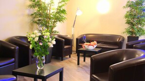 A seating area with leather chairs, a small table with a vase of flowers, and a floor lamp. - Hôtel Menton Riviera (Menton)