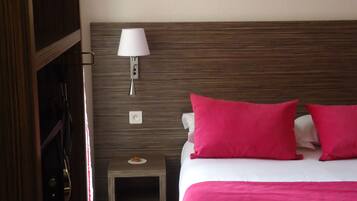 Una habitación de hotel con una cama, una mesita de noche, una lámpara y un armario.